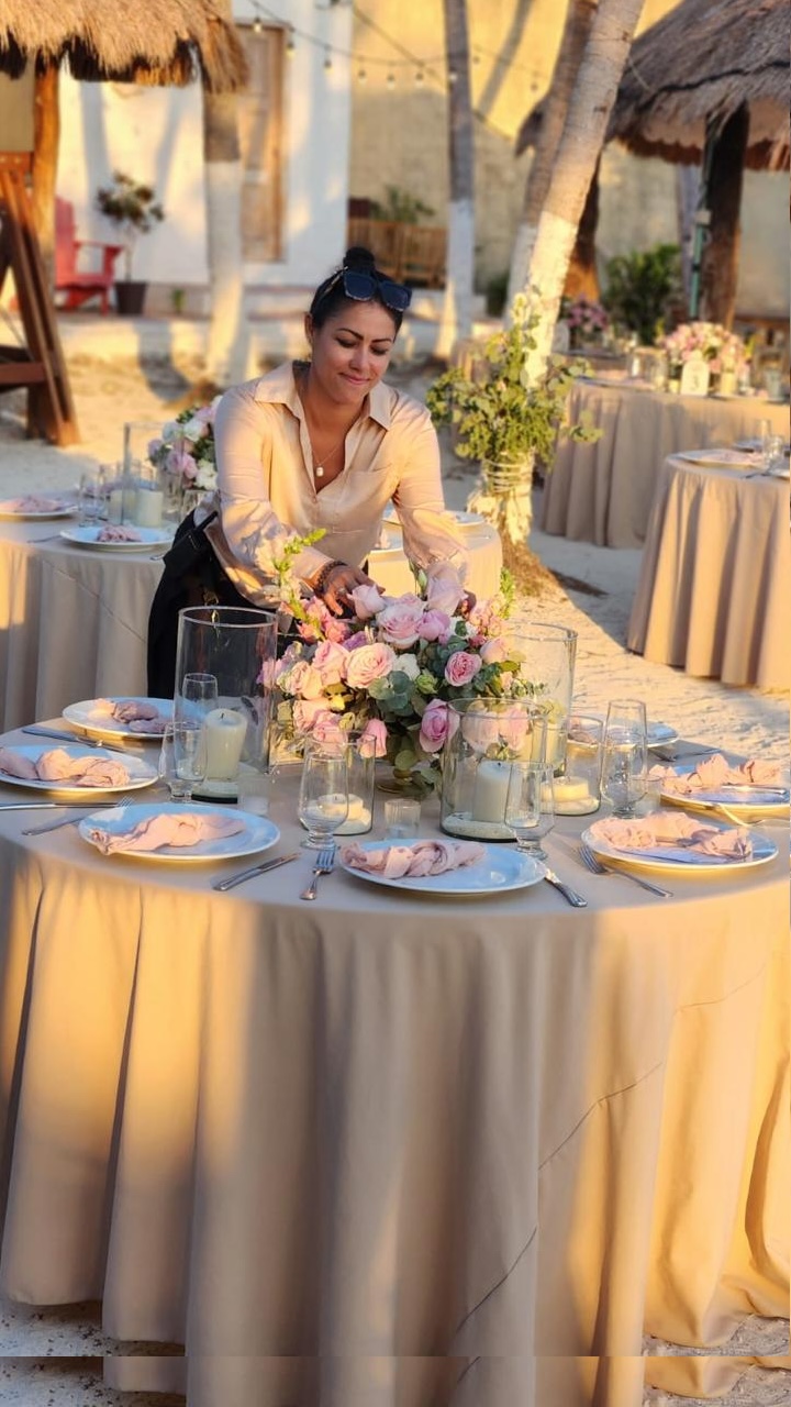Gabriela De Leon zet bloemen op een gedekte tafel op het strand